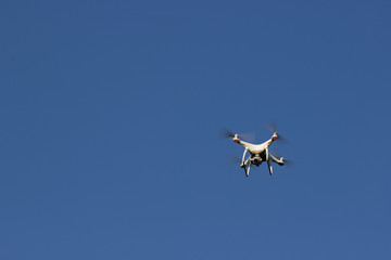 Fototapeta na wymiar White flying drone with camera on blue sky background