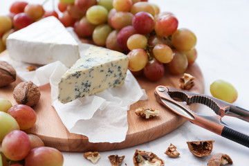 Ripe juicy grapes with cheese and walnut on wooden board