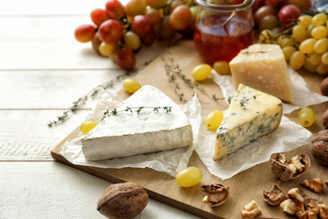 Ripe juicy grapes with cheese and walnuts on light wooden table