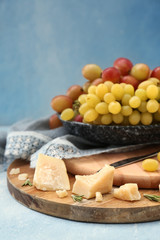 Plate with ripe juicy grapes and cheese on wooden boards