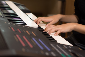 Obraz premium Young artist musician woman hands playing the electone in music room.