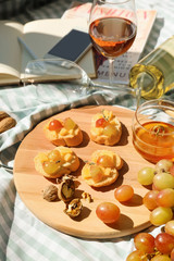 Tasty sandwiches with cheese, grape and honey on wooden board
