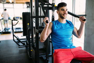Fototapeta na wymiar Fit man exercising at the gym on a machine