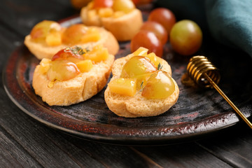 Tasty sandwiches with cheese, grape and honey on plate
