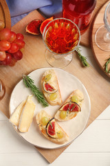 Tasty sandwiches with cheese, grape and fig on plate
