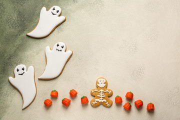 Creative cookies and candies for Halloween party on color background