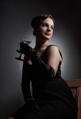 Fototapeta na wymiar Beautiful woman in black dress with glass of martini .