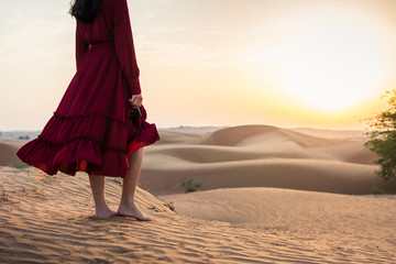 Woman walking in the desert at sunset