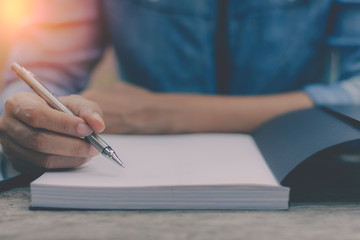 Young woman hand holding pen and concentrate on reading book with copy space in free time. Knowledge concept.
