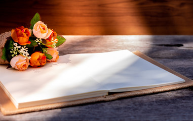 Mock up image of blank notebook and flowers on wooden table background. Space for your text.