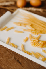 Raw pasta on the rustic wooden background. Selective focus