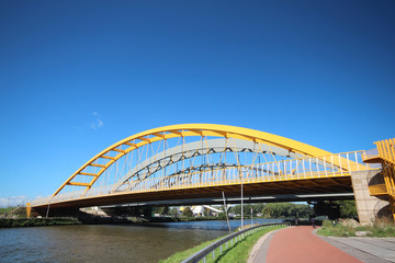 Fototapeta na wymiar Bright yellow bridge named Hogeweidebrug over the Amsterdam-Rhine canal in Utrecht for traffic and Vleutenspoorbrug which is a trainbridge.