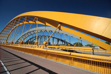 Bright yellow bridge named Hogeweidebrug over the Amsterdam-Rhine canal in Utrecht for traffic and Vleutenspoorbrug which is a trainbridge.