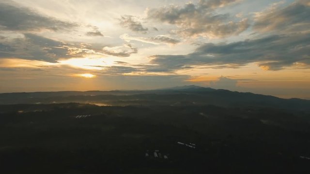 Aerial view of forest, mountains with fog, clouds at sunset on Bali,Indonesia. Tropical rainforest, trees, jungle in mountains. Fog over the jungle. Travel concept. Aerial footage.
