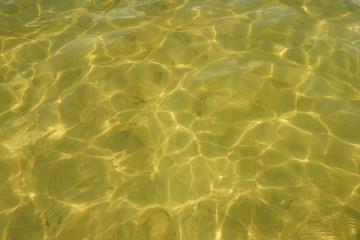 Waves and glare on the surface of the water. Shallow. Lake. Background