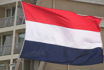 Flag of the Netherlands in the wind on a mast in the red, white and blue color.
