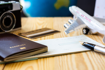 Checkbook, pen, passport, credit card, camera and airplane model mockup isolated on wooden floor background.Payment by cheque or credit card for boardingpass business, travel concept