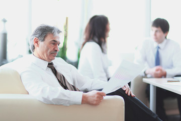 businessman pondering a document sitting in a modern office