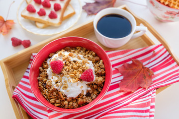 still life: granola with raspberries, toast with curd cheese and raspberries, coffee and autumn leaves
