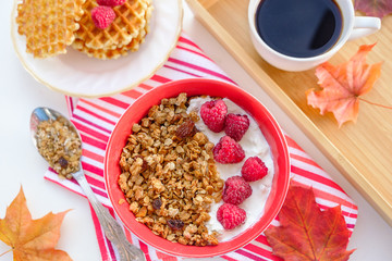 still life: granola with raspberries, waffles with raspberries and coffee surrounded by maple leaves