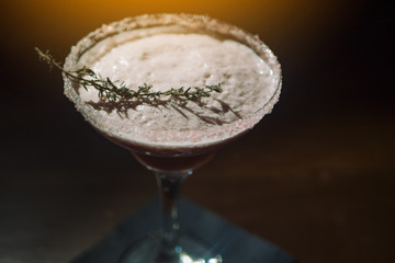 Cocktail in a beautiful glass on the table. In a dark bar