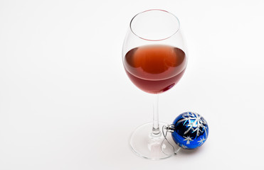 Glass with wine and christmas decoration. Winter celebration with alcohol drink. Wineglass with red liquid or wine and christmas ball ornament isolated on white background. Christmas menu concept