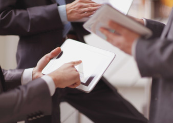 close up.a group of businessmen use their tablets to check fina