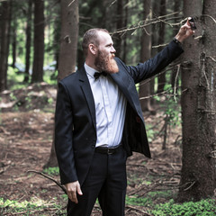 serious man in a business suit taking a selfie in a forest.