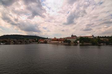 Panoramic view of historical center of Prague, Charles Bridge and Vltava river, Saint Vitus Cathedral at cloudy summer day. Buildings, cathedrals and landmarks of old town, Prague, Czech Republic