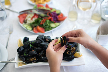 Women's hands open of boiled mussels served on the table. Albania. Adriatic coast. National food.