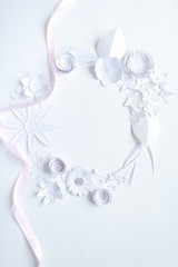 frame with white paper flowers and pink ribbon on white background. Cut from paper.
