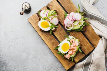 Open sandwiches on dark rye bread with eggs, shrimps, radishes, cucumber, cream cheese and arugula...