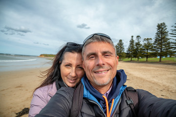 Couple in the 40s happy on the beach making selfie