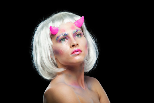 Halloween. Portrait of young beautiful girl with make-up. With white hair and pink devil horns. Isolated on black background.