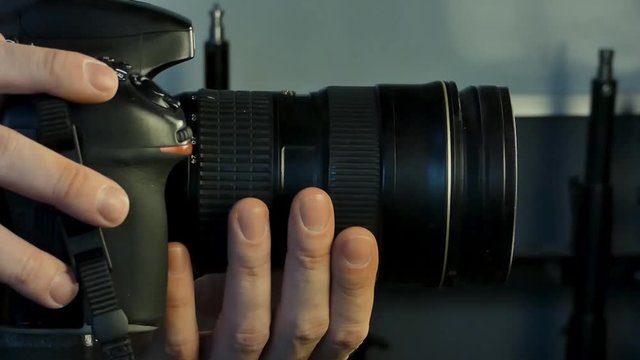photographer in the studio working with the camera adjusting the lens, profile view, close-up