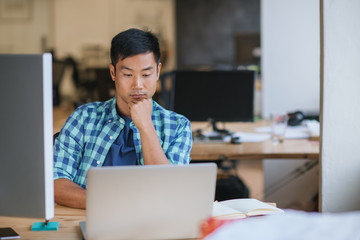 Asian designer sitting at his office desk focused on work 