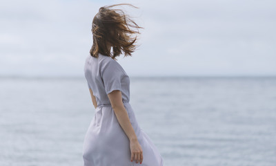 Woman in dress enjoys a walking near the sea shore.