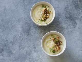 Cauliflower cream soup , decorated with fried cauliflower inflorescence in white bowls  on a gray background. Top view. Copy space