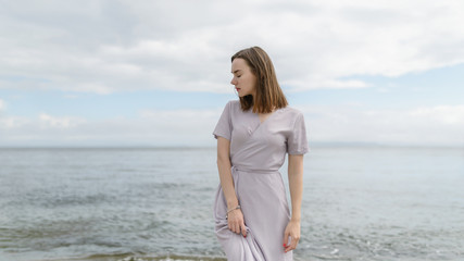 Woman in dress enjoys a walking near the sea shore.