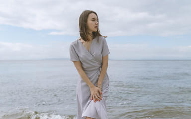 Woman in dress enjoys a walking near the sea shore.