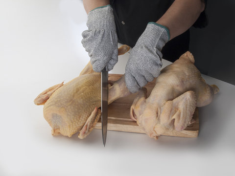 Cortando pollos con guantes y cuchillo sobre tabla detalle