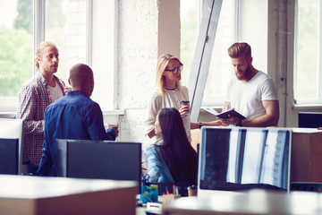 Happy to work together. Group of young business people communicating while working in the office.