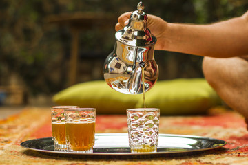 Tea pouring into glass from metal teapot