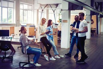 Happy to work together. Group of young business people communicating while working in the office.