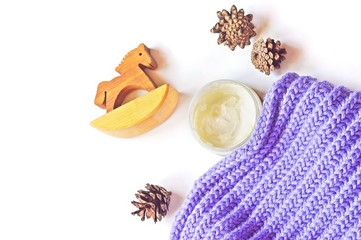 Autumn and winter skin care/  Organic skin care cosmetics. Autumn and winter face cream jar, purple woolen scarf, toy wooden horse and pine cones. Flat lay beauty photo