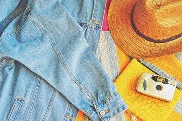 Stylish women's clothes/ Blue denim jacket, hat, yellow bag and vintage camera. Flat lay photo for fashion blog