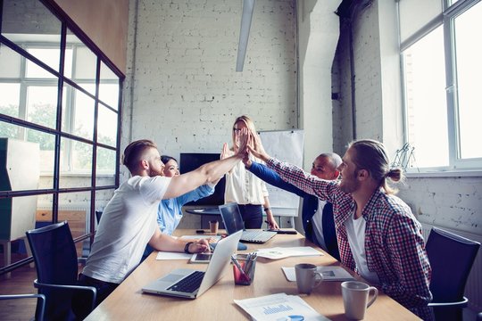 Happy successful multiracial business team giving a high fives gesture as they laugh and cheer their success.