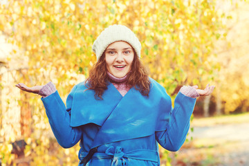 Surprised woman at autumn park, presenting something on empty palms. Autumn season. Woman in blue...
