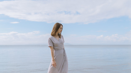 Woman in dress enjoys a walking near the sea shore.