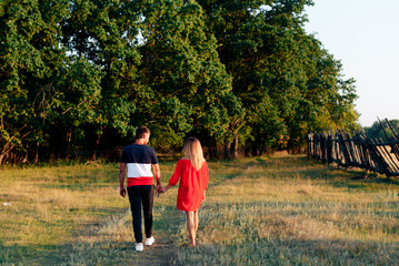 Obraz premium Young beautiful enamored couple walking outdoors in summer at sunset